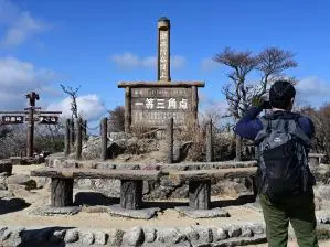 写真2 三角点の看板。中身は虚ろか... 右の親父サンのザックは60Literとある。 写真2 三角点の看板